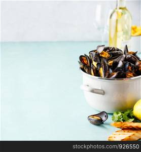 Belgian mussels in white wine with lemon, herbs, croutons and french fries on blue background, copy space