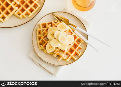 Belgian waffles with banana and condensed milk on white table. Top view