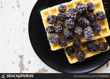 Belgian waffles with blackberries on the old wooden table, close-up.. Belgian waffles with blackberry