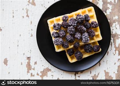 Belgian waffles with blackberry on an old wooden table.. Belgian waffles with blackberry