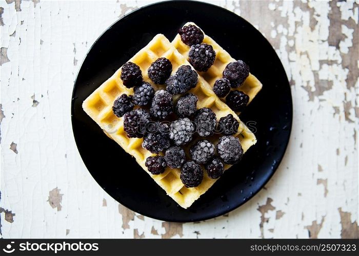 Belgian waffles with blackberry on an old wooden table.. Belgian waffles with blackberry