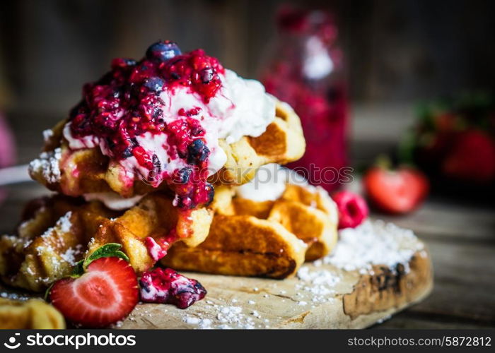 Belgian waffles with fresh berries on rustic wooden background