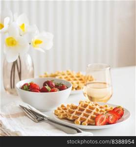 Belgian waffles with strawberry and powdered sugar on white plate. Breakfast food concept