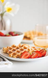 Belgian waffles with strawberry and powdered sugar on white plate. Breakfast food concept