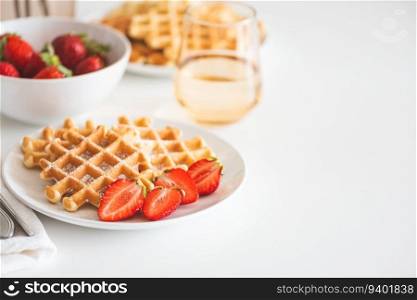 Belgian waffles with strawberry and powdered sugar on white plate. Breakfast food concept. Copy space