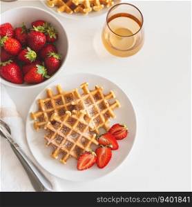 Belgian waffles with strawberry and powdered sugar on white plate. Breakfast food concept. Top view