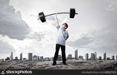 Believe in yourself. Cute boy of school age lifting barbell above head