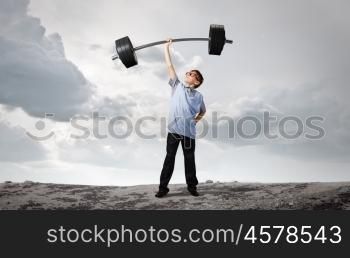 Believe in yourself. Cute boy of school age lifting barbell above head