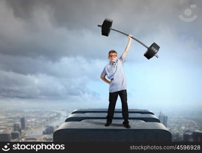 Believe in yourself. Cute boy of school age lifting barbell above head