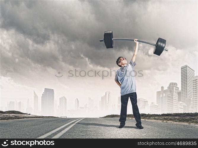 Believe in yourself. Cute boy of school age lifting barbell above head