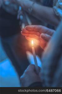 Believer in a church with candle, closeup photo of a woman covers the flame of the candle with her hand, asks for help from God on the Easter holiday. Believer in a church with candle