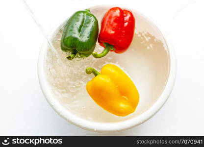 Bell pepper soaked in water. Washing fresh vegetables on white background.
