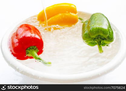 Bell pepper soaked in water. Washing fresh vegetables on white background.