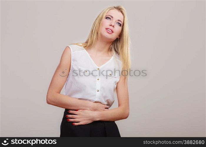 Bellyache, indigestion or menstruation. woman suffering from stomach pain studio shot on gray