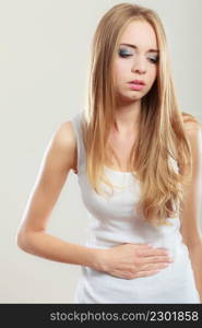 Bellyache, indigestion or menstruation. Young woman suffering from stomach pain studio shot on gray