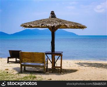 Bench and a sunshade umbrella on the tropical beach