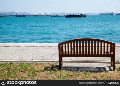 Bench by the sea. Parked in front of the boat in the sea, many ships.