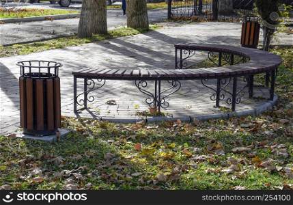 bench in an autumn park. Pavement of tiles and garbage can. bench in an autumn park. Pavement of tiles and garbage can.