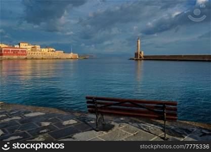 Bench in picturesque old port of Chania is one of landmarks and tourist destinations of Crete island in the morning on sunrise. Chania, Crete, Greece. Picturesque old port of Chania, Crete island. Greece