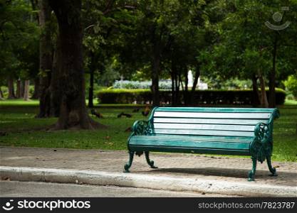 Bench in the park on the pavement. Within the park. Shady trees and the relax.