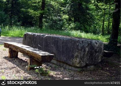 Bench makes stone with wooden seats in the forest of Belgium.