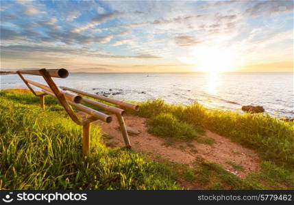 bench on sea coast at sunrice