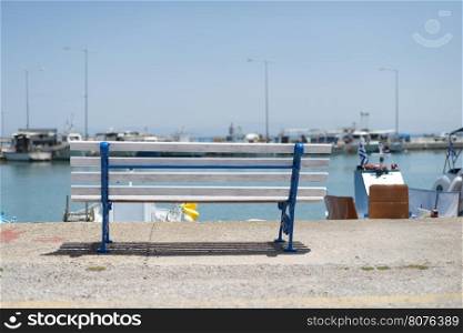Bench on the beach and boats. Blue sky