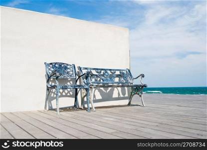 Bench on wooden floor with white wall in the beach.