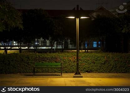 Bench under lamp In a park during the night.