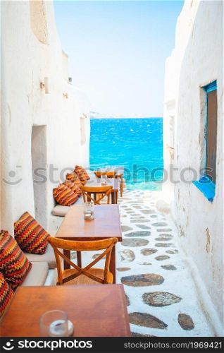 Benches with pillows in a typical greek outdoor cafe in Mykonos with amazing sea view on Cyclades islands. Typical Greek bar in Mykonos town with sea view, Cyclades islands, Greece