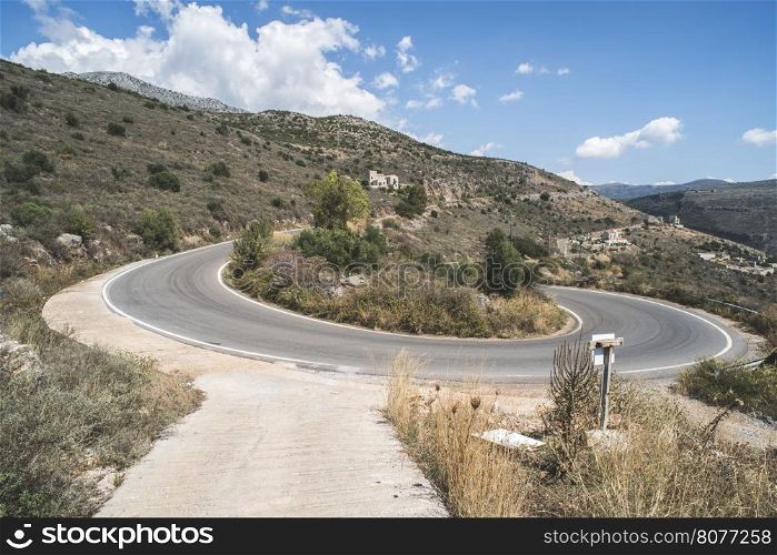 Bend in the mountain road. Blue cloudy sky. Greece