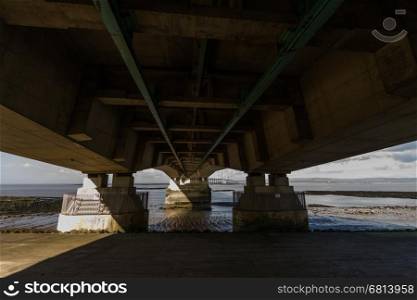 Beneath the Second Severn crossing is a bridge that carries the M4 motorway over the Bristol Channel or River Severn Estuary between England and Wales, United Kingdom. Morning light from the east.