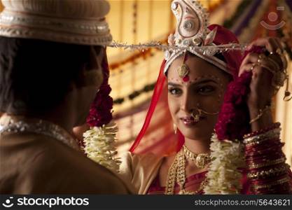 Bengali bride putting a garland on groom