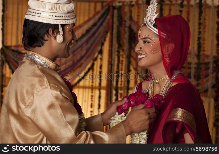 Bengali groom putting a garland on a bride