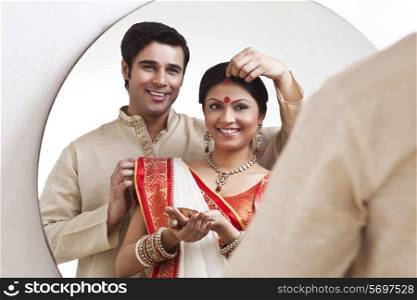Bengali man putting sindoor on wife&rsquo;s forehead