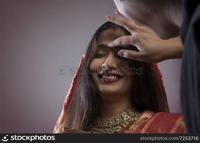Bengali man putting sindoor on wife s forehead