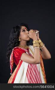 Bengali woman blowing on a conch shell