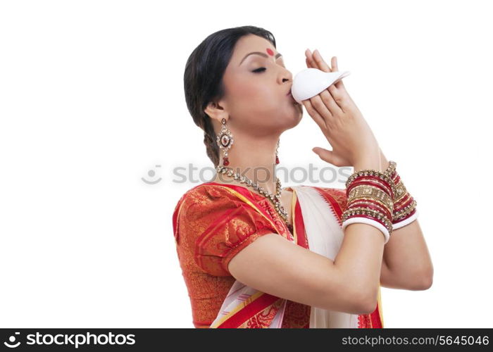 Bengali woman blowing on a conch shell