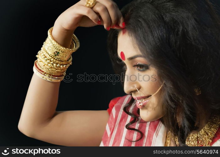 Bengali woman putting sindoor on her forehead