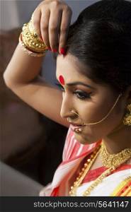 Bengali woman putting sindoor on her forehead