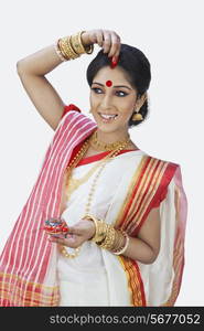 Bengali woman putting sindoor on her forehead