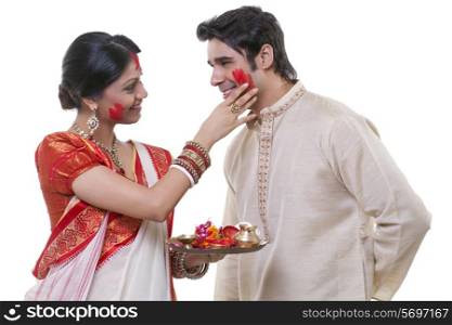 Bengali woman putting sindoor on man&rsquo;s face