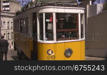 Bergauffahrende gelbe Tram in Lissabon, rechts und links Mauern, dann HSuser.