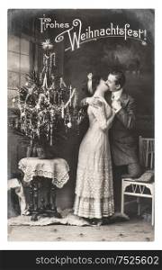 BERLIN, GERMANY - CIRCA 1911: rare antique german postcard showing young couple celebrated with christmas tree. Vintage picture from ca. 1911, in Berlin, Germany