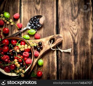 Berries in a Cup on the Board. On wooden background.. Berries in a Cup on the Board.
