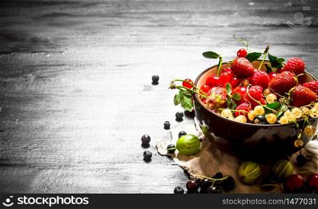 Berries in a Cup on the old fabric. On a black wooden background.. Berries in a Cup on the old fabric.