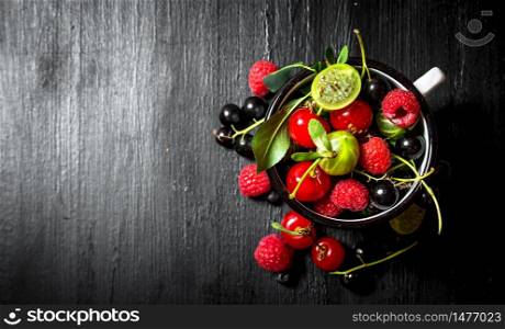 Berries in a mug. On a black wooden background.. Berries in a mug. On black wooden background.