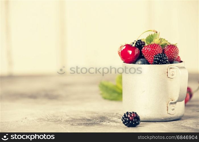 Berries in a rustic mug on a table. Berries in a rustic mug
