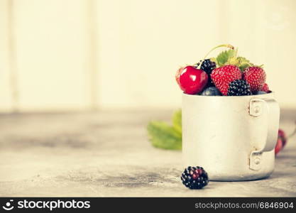 Berries in a rustic mug on a table. Berries in a rustic mug