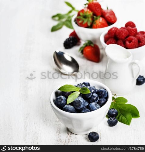 Berries in bowls on Wooden Background. Strawberries, Raspberries and Blueberries. Health, Diet, Gardening, Harvest Concept